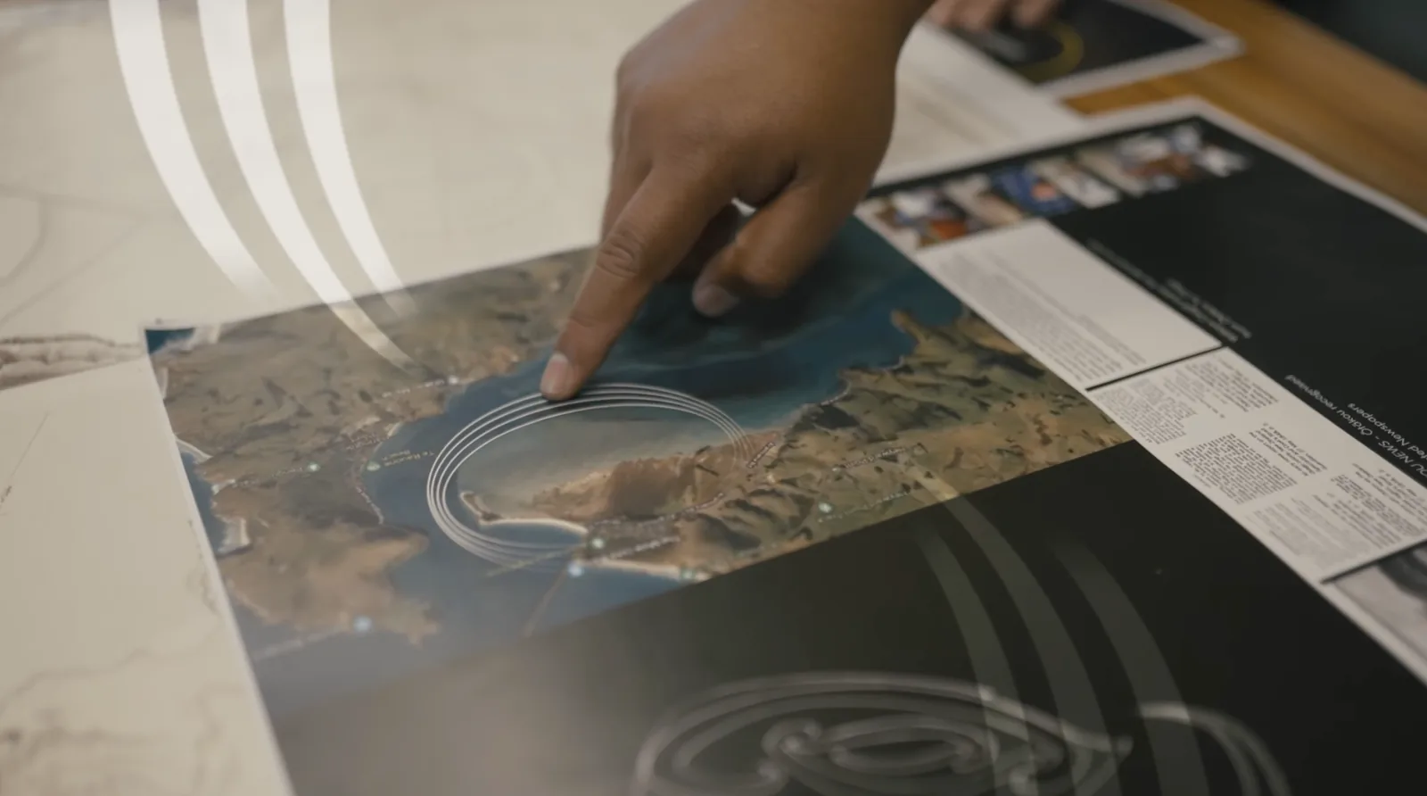 Tuakiritaka - hand tracing Te Rauone on a satellite map of the Ōtākou harbour, layered with kowhaiwhai motifs